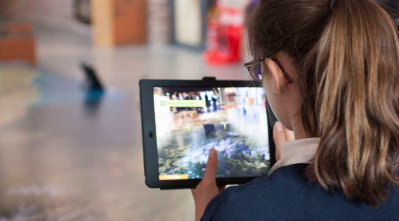 School aged girl looking at an immersive digital experience on an Ipad
