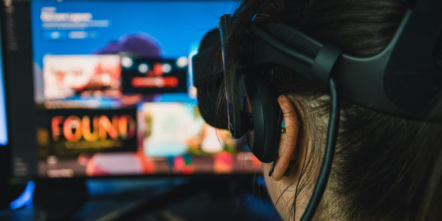 Person wearing a VR headset looking at a computer screen displaying a game selection menu.