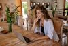 A woman working remotely on her laptop in a bright, relaxed home setting.
