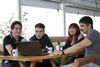 A group of colleagues collaborating around a laptop at an outdoor workspace.