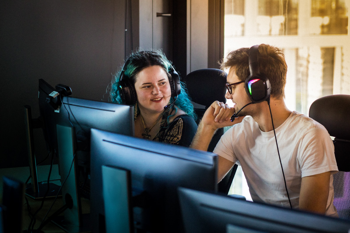 Two people with headsets on a computer
