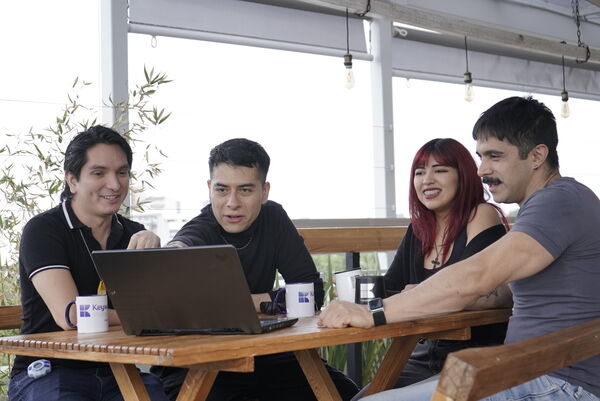 A group of colleagues collaborating around a laptop at an outdoor workspace.