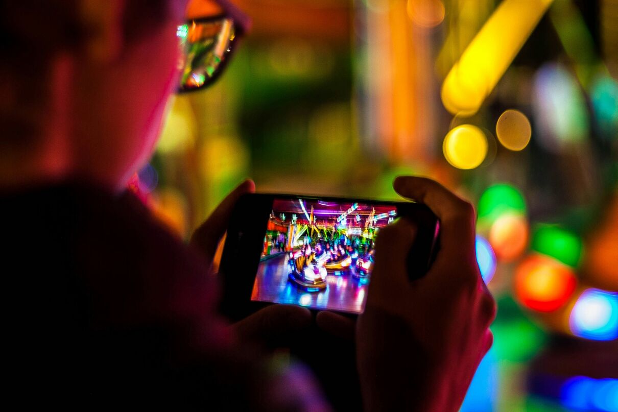 You can see the profile of a man, holding a mobile phone playing a game.