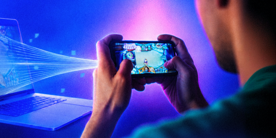Someone playing on a mobile phone with a light beam projecting to a computer