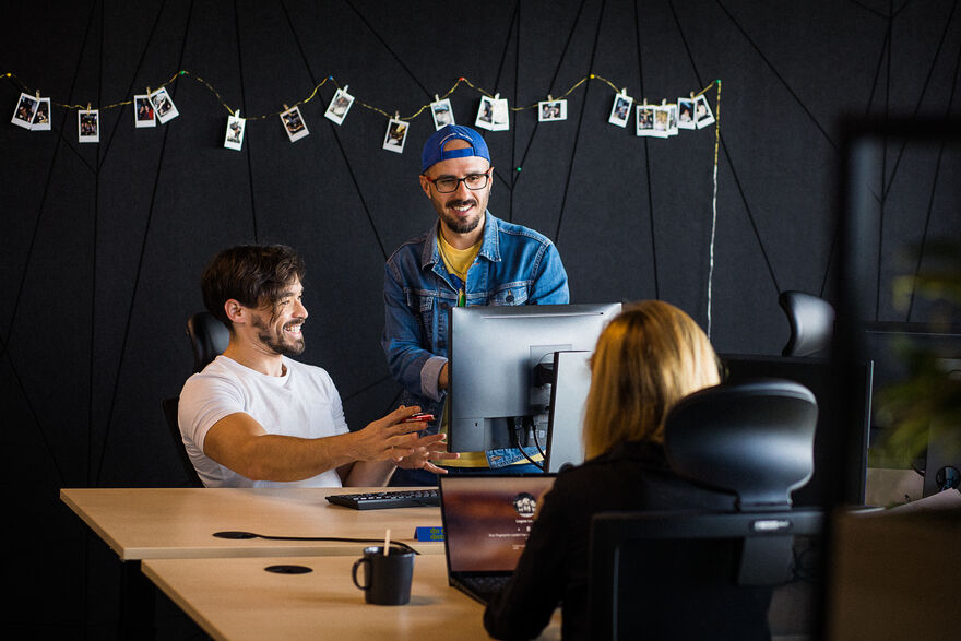 Three people sitting at a conference table on a computer
