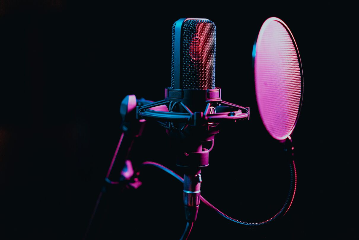 Professional studio microphone with pop filter under colourful lighting.